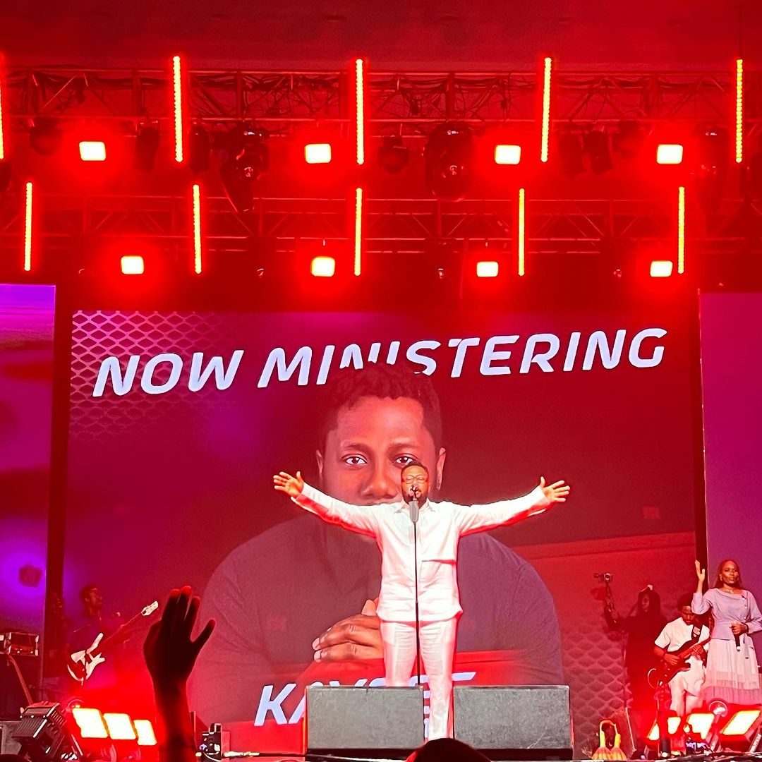 Performer in front of a large LED screen under red stage lighting